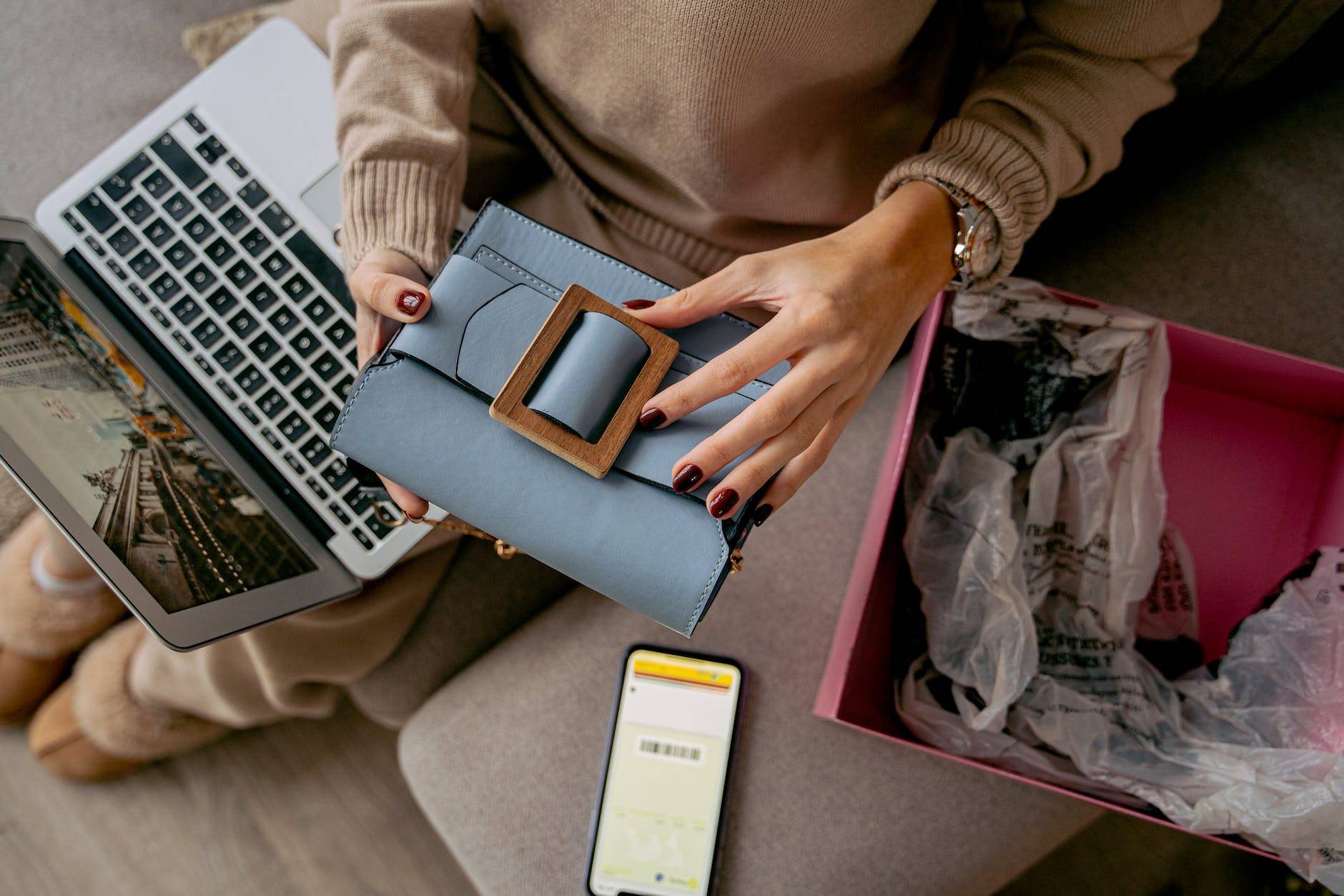 woman sitting on a couch with a laptop on her lap and holding a new purchase